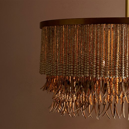 The Baja chandelier pairs organic ease (wood beads, coconut-shell fringe) with metallic sophistication (the brass-finish iron frame).
